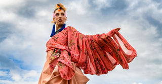 Fashion model wearing a flowing coral blouse designed by SKYE|AIRE.