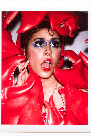 Close up of model's face surrounded by red pleather lobster claws by fashion designer Cardiovascuwhore.