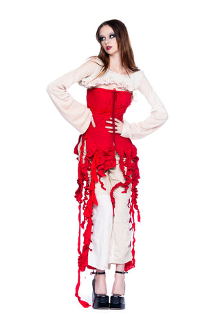 Model standing with hands on hips while wearing red and white avant garde clothing from designer Cardiovascuwhore.