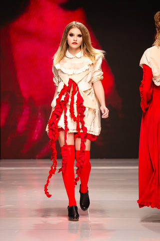 Model walking down a runway wearing a white and red dress by fashion designer Cardiovascuwhore.