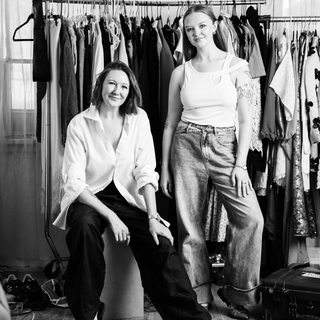 Black and white photo Co-founders of ShowHaus, Sami and Heather in front of a rack of designer clothing.