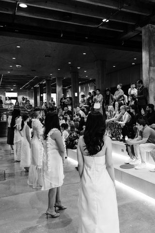 Black and white image of a runway collection lineup standing in front of the attendees.