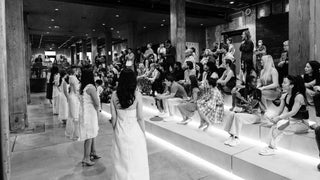 Black and white image of a runway collection lineup standing in front of the attendees.