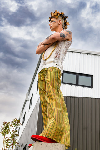 Masc fashion model wearing yellow and green striped pants and red shoes by Skye Aire