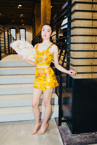 Model standing in front of stairs wearing a short yellow dress from fashion brand Thenso.