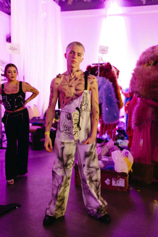 A behind the scenes shot of a masc model at a fashion show wearing designer Thenso.