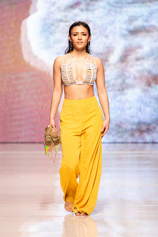 model walking down the runway wearing a knit bra top and yellow flowing pants by Yet Luxxe.