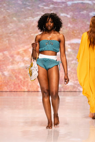 Model walking down the runway wearing a knit bathing suit from Yet Luxxe.