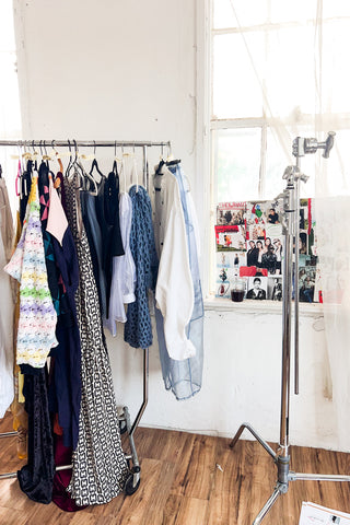 A clothing rack in a photography studio full of designer clothing.